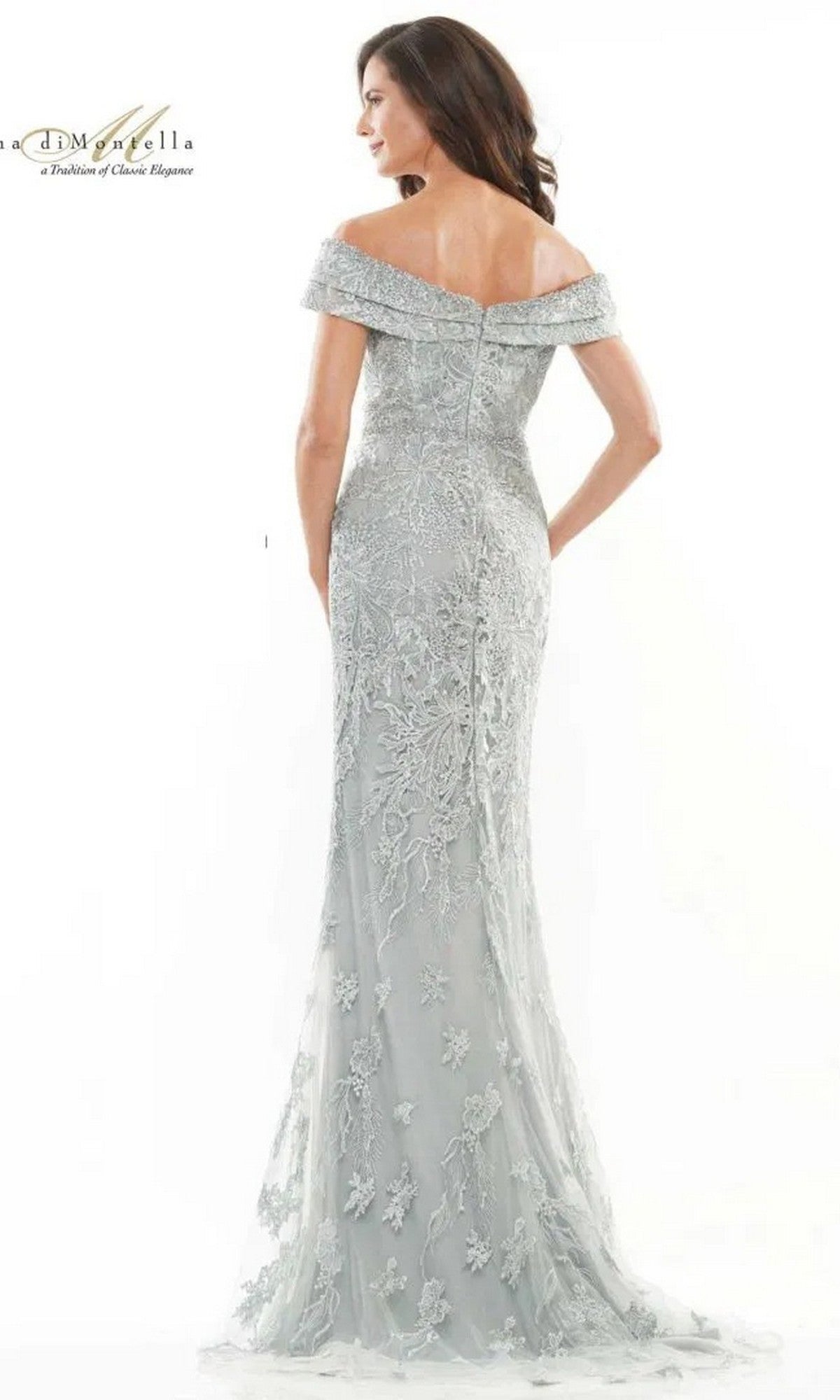 A woman is seen from the back wearing the Rina Di Montella RD2737, a long formal dress in light gray with off-the-shoulder design, sheer lace, floral embroidery, and a beaded waist.